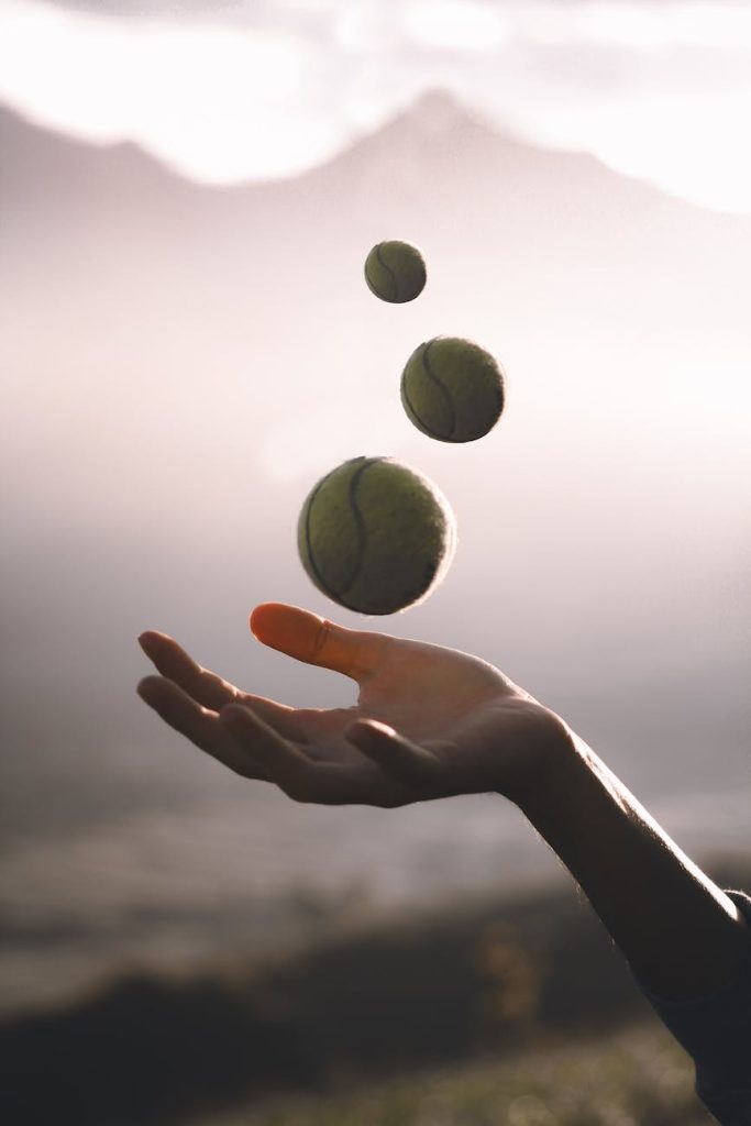 crop sportswoman juggling tennis balls on meadow
